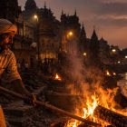 a Dom worker tending a burning pyre at Manikarnika Ghat, Varanasi