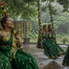 Women in green sarees singing on decorated swings during monsoon