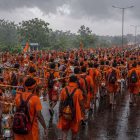 Kanwariyas in saffron clothes walking on a highway during monsoon