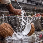 A coconut being broken on temple steps, water splashing out.