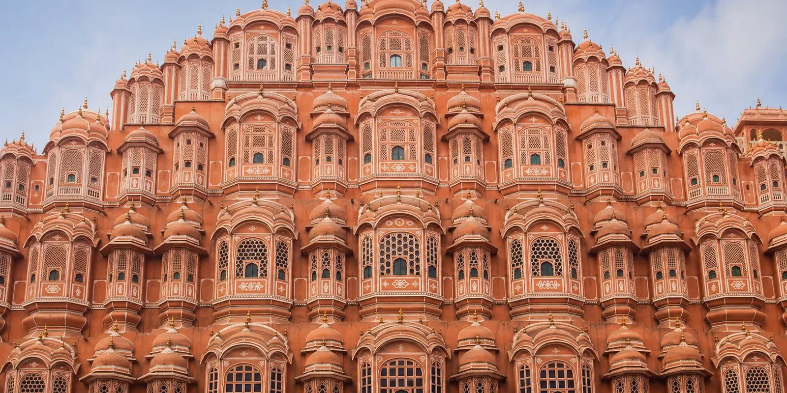 the pink sandstone front of Hawa Mahal in Jaipur, covered in small jaali windows