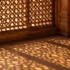 Sunlight passing through an old sandstone jaali screen, casting patterns on the floor