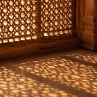 Sunlight passing through an old sandstone jaali screen, casting patterns on the floor