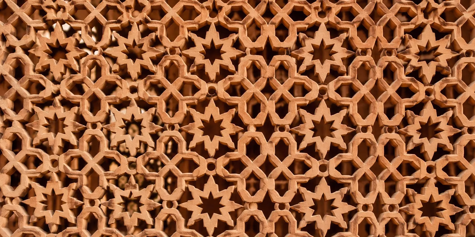 a close-up of a carved sandstone jaali screen with a repeating geometric pattern