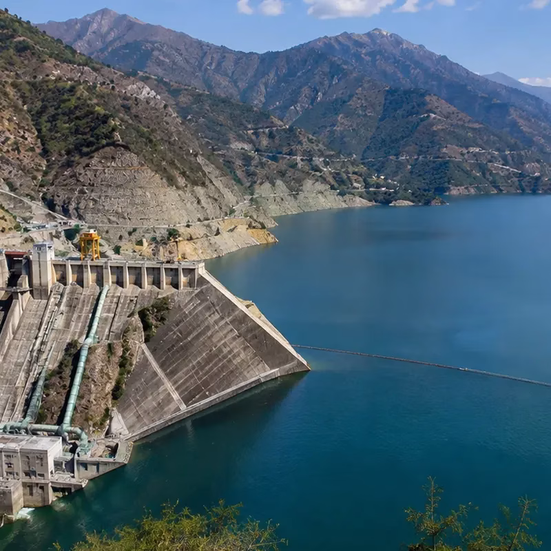 The Tehri reservoir at dusk, with calm water stretching between the Himalayan hills